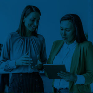 Two businesswomen discussing information on a tablet.