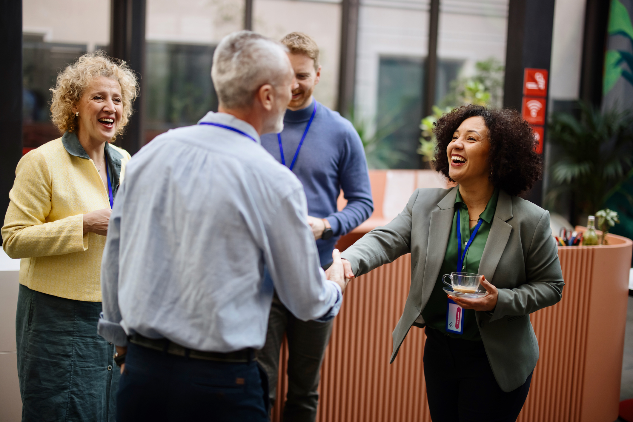 A group of people in an office setting. A man and woman are shaking hands.