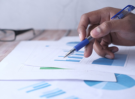 Hand holding a pen reviewing financial documents