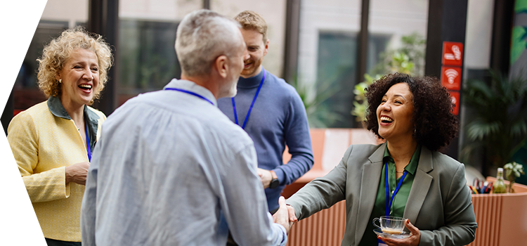 A group of people in an office setting. A man and woman are shaking hands.