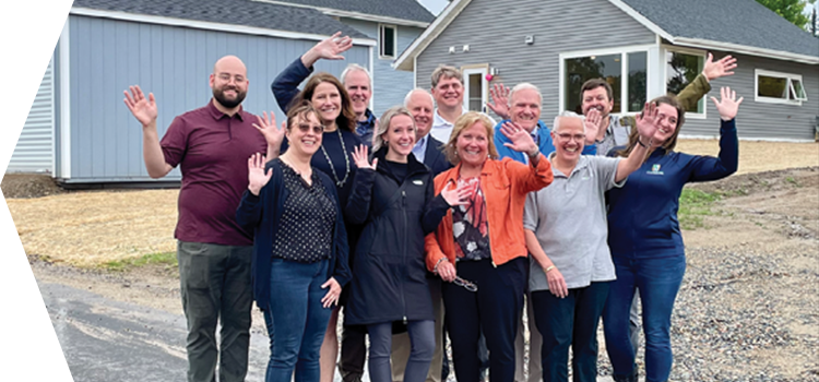 Group of people waving in front of a new housing development