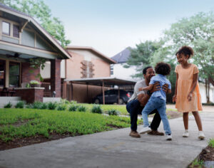 Man playing with children on sidewalk in front of home