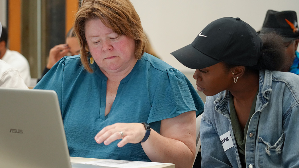 Two attendees looking at a laptop learning about a pro forma