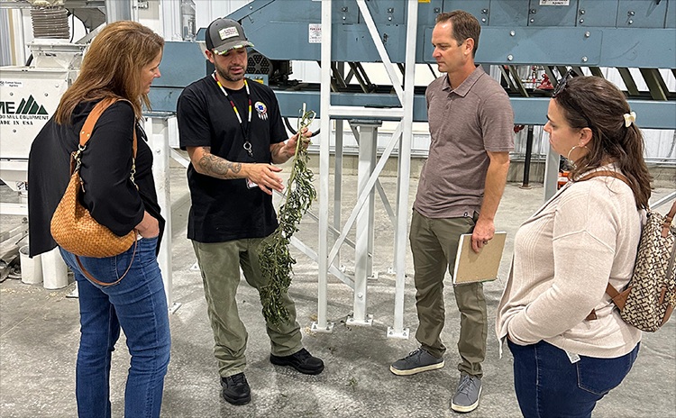 Inside a production facility with staff looking at man holding a brand of hemp