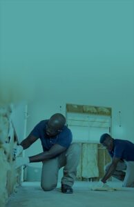 Two men kneeling to install insulation in a room 